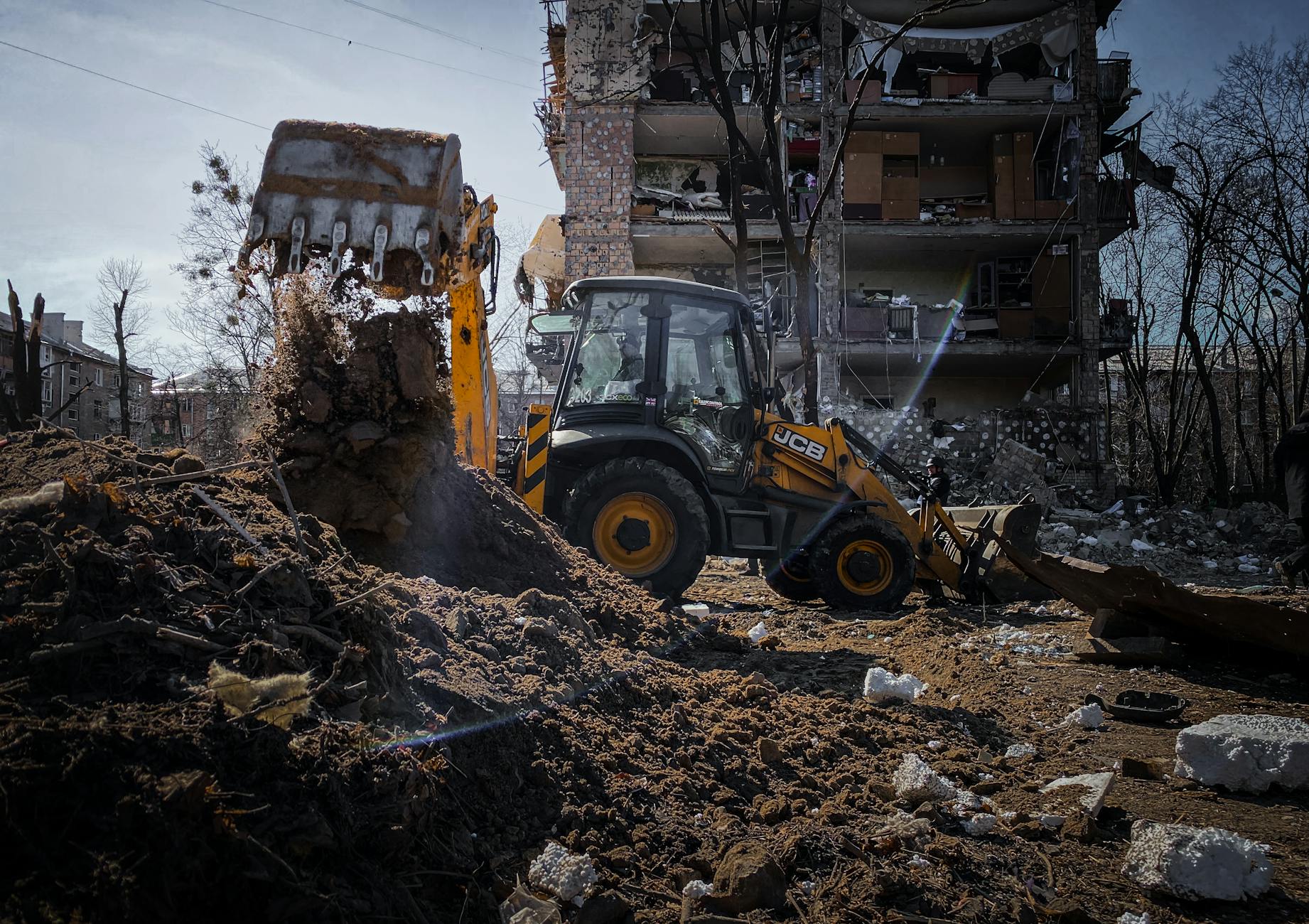 yellow excavator digging rubble of a ruined house